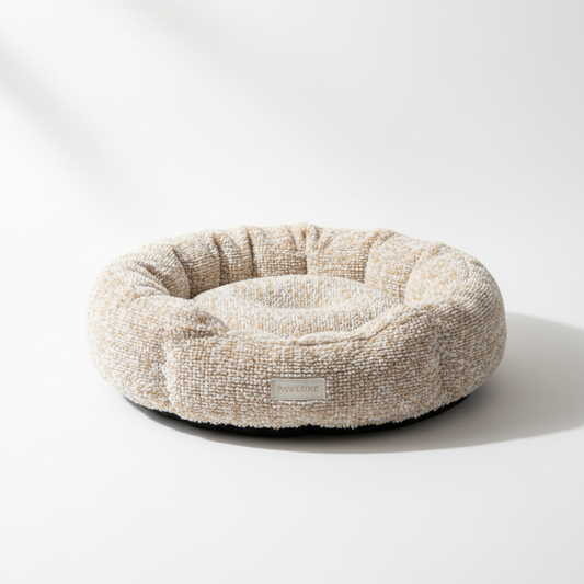 A round soft plush cat bed in warm beige and cream tones